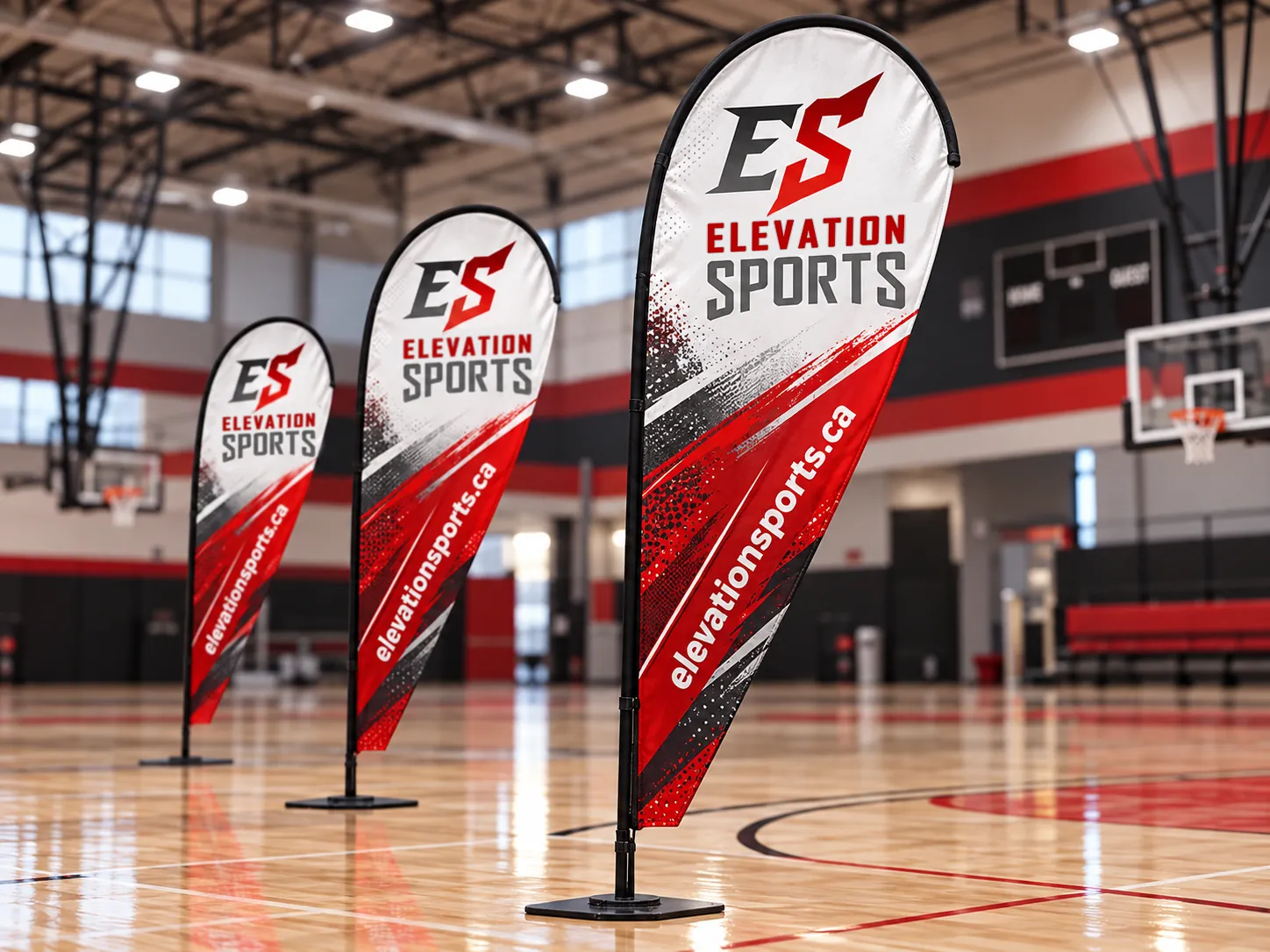 Three red, black and white teardrop banners with the Elevation Sports logo and website, standing on a gym court.